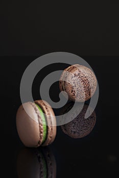 There are two chocolate cocoa flavored macarons on the black table