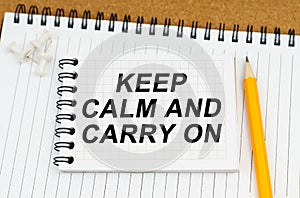 There are two notebooks and a pencil on the table. On the top notepad, the inscription - Keep Calm And Carry On