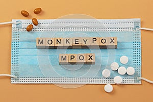 The words Monkeypox and Mpox are laid out with wooden cubes on a surgical face mask. photo