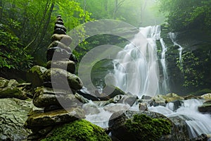 There is a waterfall behind and a pile of rocks in the foreground