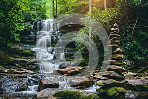 There is a waterfall behind and a pile of rocks in the foreground