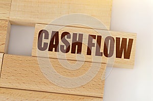 There is a wooden Jenga on the table, on one Jenga it is written - CASH FLOW