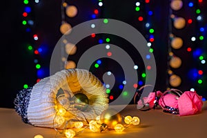 There are wool hat, different colors balls and lights on the table/background. There are pink candy and different colors lights.