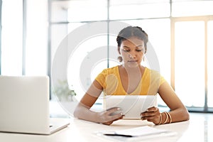 Theres an app to help complete any business task. a young businesswoman using a laptop and digital tablet at her desk in