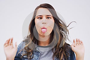 Theres a comedienne in all of us. Studio shot of a young woman making a funny face against a gray background.