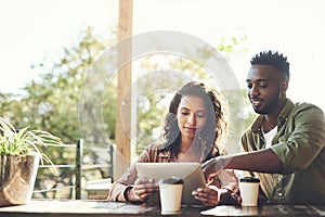 Theres lots to connect over on the net. a young couple using a digital tablet together at a cafe.