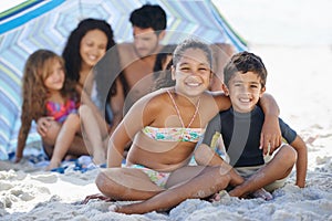 Theres no better place to be. A family of five sitting under their umbrella at the beach.