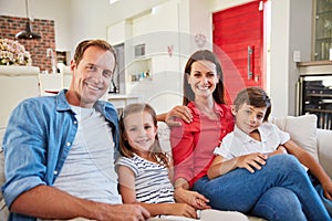 Theres no greater joy than family. Portrait of smiling parents sitting with their young son and daughter on their living