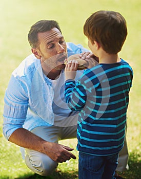 Theres no I in food. a father and son eating a burger outside.