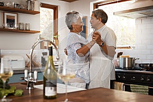Theres no right or wrong place for romance. a happy mature couple dancing together while cooking in the kitchen at home.