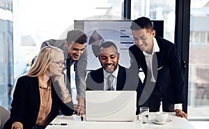 Theres nothing that cant be solved with teamwork. a group of young businesspeople using a laptop during a meeting in the