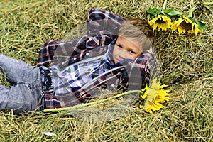 Theres nothing like the peace of the contryside. Little boy enjoy vacation in countryside. Little boy relax on hay. Live