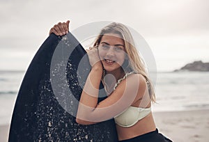 Theres nothing a little wave therapy cant fix. a young woman standing on the beach with her surfboard.