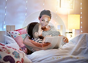 Theres time for another one.... Shot of an attractive young pregnant woman reading her daughter a bedtime story on a