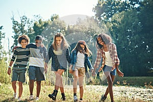 Theres a world of fun waiting for you in nature. a group of teenagers walking through nature together at summer camp.