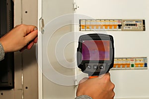 thermal imaging inspection of electrical equipment. Close-up shot of man hand recording heat loss with infrared thermal