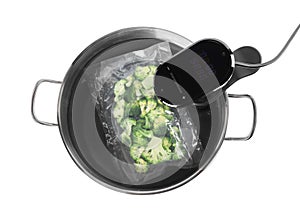 Thermal immersion circulator and vacuum packed broccoli in pot on white background, top view. Sous vide cooking