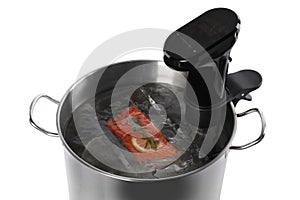 Thermal immersion circulator and vacuum packed salmon in pot on white background. Sous vide cooking