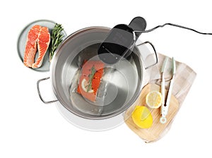 Thermal immersion circulator and vacuum packed salmon in pot on white background, top view. Sous vide cooking