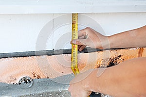 Thermal insulation house foundation walls with styrofoam boards. Worker use ruller to measure the correct length of styrofoam.