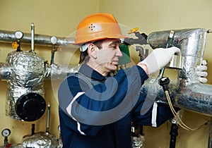 Thermal insulation. worker insulating heating system pipes with foil