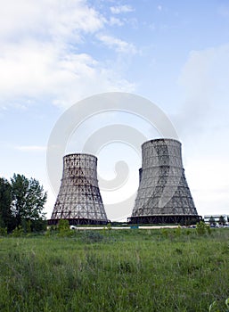 Thermal power station, cogeneration plant, two cooling towers from which smoke comes. Green grass, blue sky