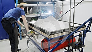 Thermoforming machine. The worker makes the form or part for the robot