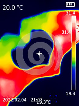 A A thermographic image of a hand with a human heart, showing different temperatures in different colors, from blue indicating