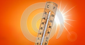 Thermometer against orange background with hot summer sun. photo