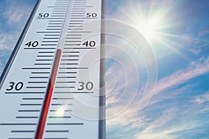 Thermometer against sky with sun in hot weather