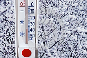 The thermometer on the background of a snow-covered tree shows minus 35 degrees. Heavy frost, difficult weather conditions_