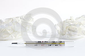 Thermometer close-up on white background. Glass mercury thermometer with celsius degree and napkins. Illness concept