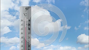 Thermometer with cloud timelaps in the background shows increasing temperature.