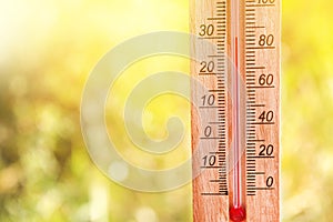 Thermometer displaying high 30 degree hot temperatures in sun summer day.