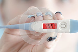 Thermometer in female hand. Hyperthermia. Face on background