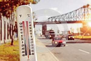 Thermometer in front of cars and traffic during heatwave