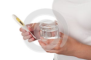 Thermometer and a glass of water in girl hands isolated