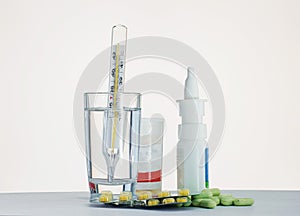 Thermometer in a glass of water and medication for the table