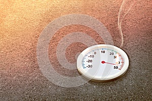 Thermometer with high temperature on the street with glowing sun background