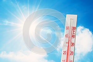 Thermometer is hot in the sky bright sun, glowing rays, concept of extreme weather