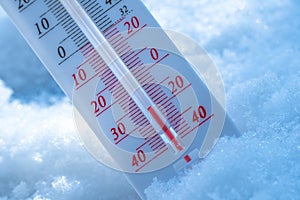 The thermometer lies on the snow in winter showing a negative temperature. Meteorological conditions in a harsh climate in winter