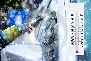 Thermometer or meteorological indicator in winter near the car shows low temperatures