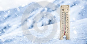 Thermometer on the mountains in the snow shows temperatures below zero. Low temperatures in degrees Celsius and fahrenheit in