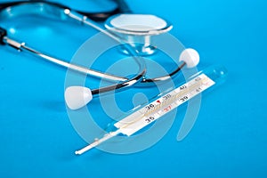 Thermometer and phonendoscop on a blue background