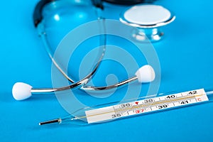 Thermometer and phonendoscop on a blue background