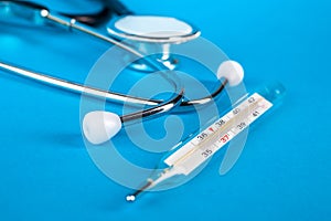 Thermometer and phonendoscop on a blue background