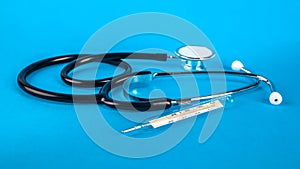 Thermometer and phonendoscop on a blue background