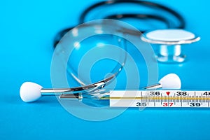 Thermometer and phonendoscop on a blue background