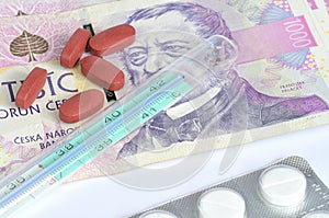 Thermometer, pills and czech banknotes money currency texture background