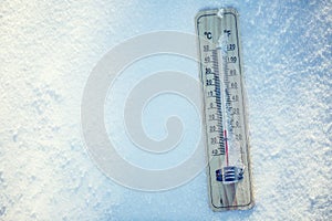 Thermometer on snow shows low temperatures under zero. Low temperatures in degrees Celsius and fahrenheit.